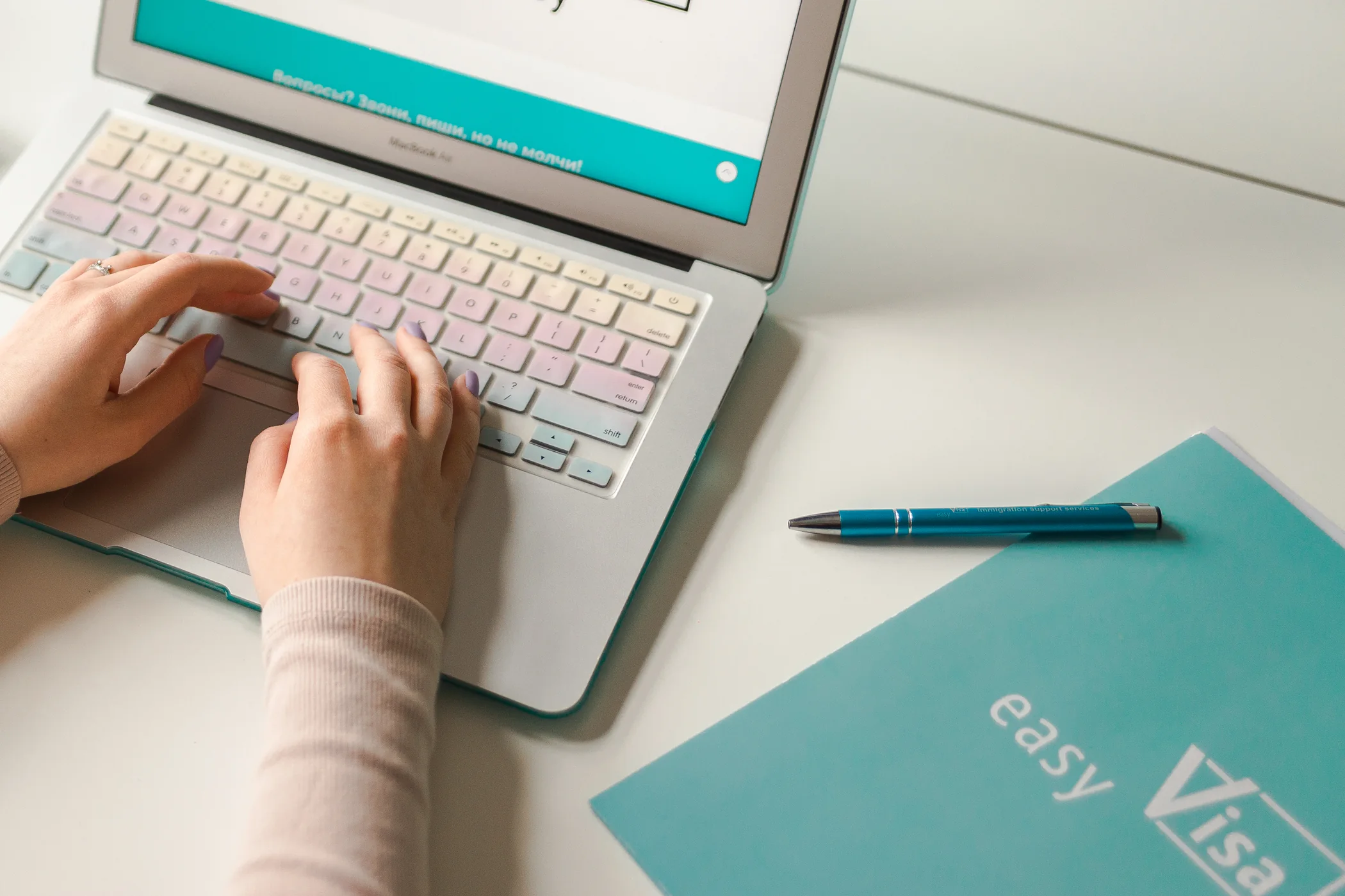 Preparing documents at a laptop beside an Easy Visa folder and pen